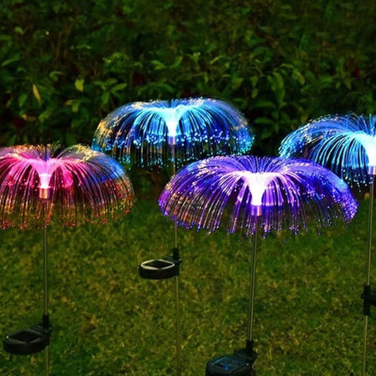 Lámparas solares de fibra óptica tipo medusa iluminando un jardín de noche